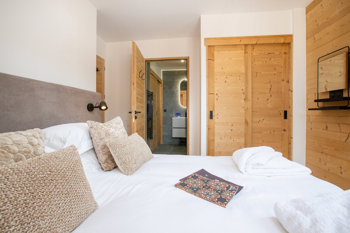 A bedroom with a sliding wooden door leading to a bathroom