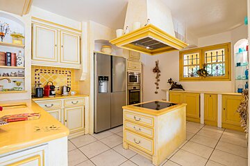 A kitchen with yellow cabinets and a stainless steel refrigerator