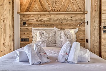 A bed with white towels and a wooden headboard