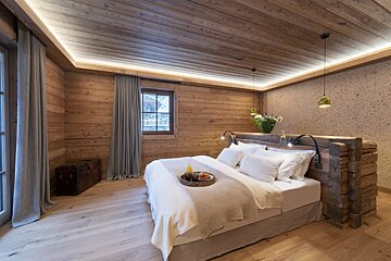 A bedroom with wood paneling and a bed with a tray of food on it