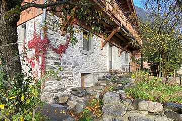 A stone building with a wooden roof and a tree in front of it
