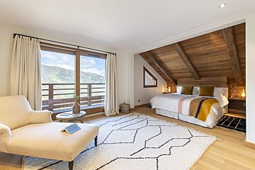 A bedroom with a large bed and a chair with a book on it