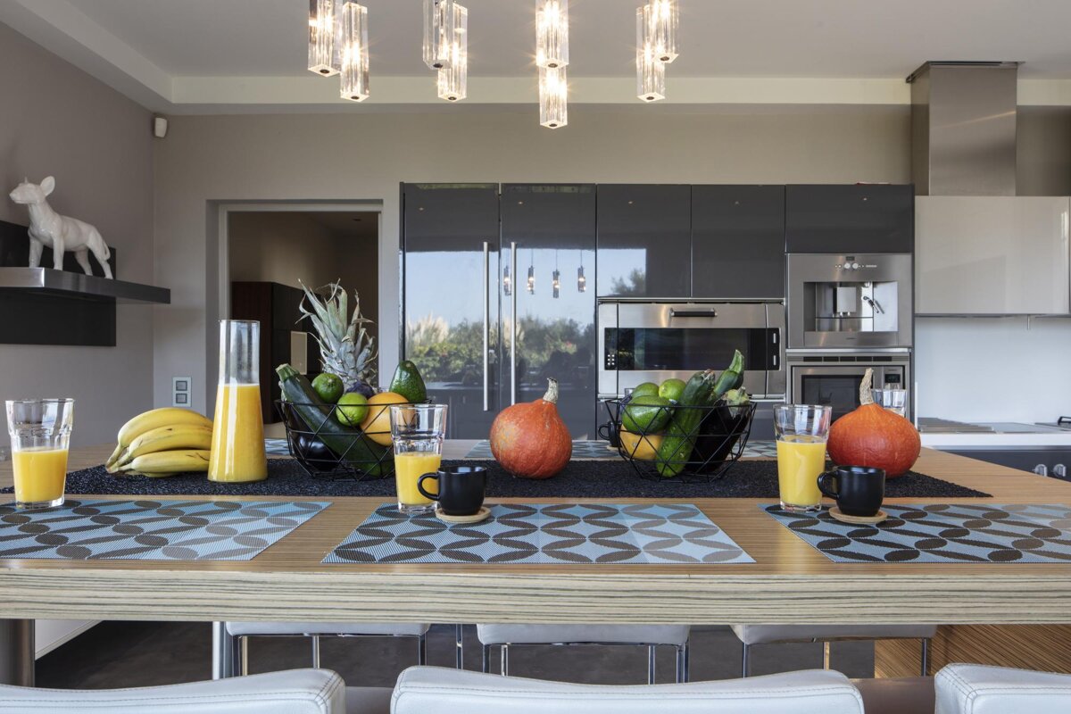 A kitchen table with a bowl of fruit and a bottle of orange juice
