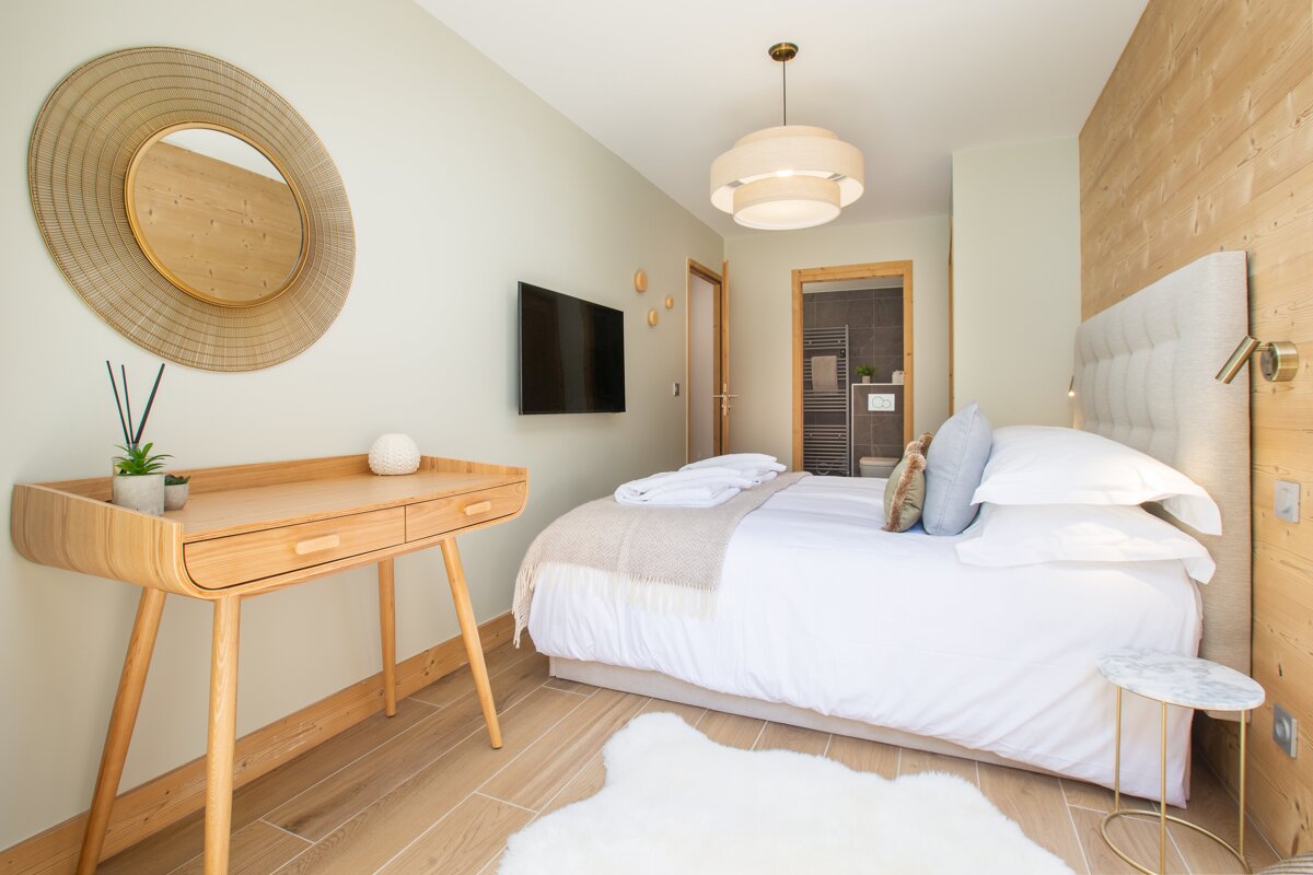 A bedroom with a bed a desk and a flat screen tv