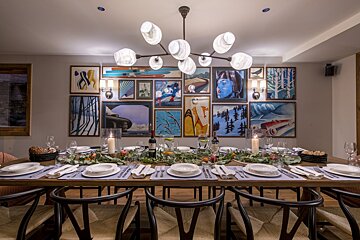 A dining room with a table and chairs and paintings on the wall
