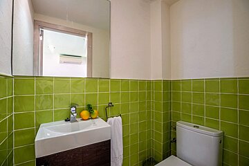 A bathroom with green tiles and a sink and toilet