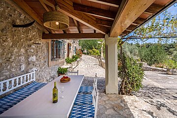 A bottle of wine sits on a table under a wooden roof