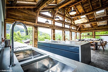 A kitchen with a stainless steel sink and a wooden ceiling