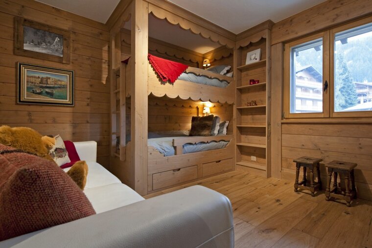 A bunk bed in a wooden room with a white couch
