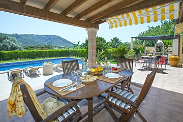 A table and chairs on a patio with a yellow and white awning