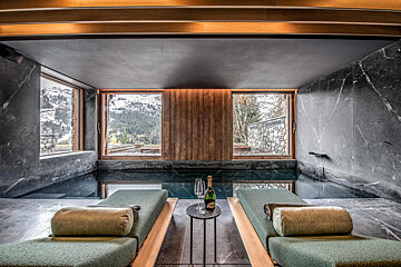 A bottle of champagne sits on a table in front of a swimming pool