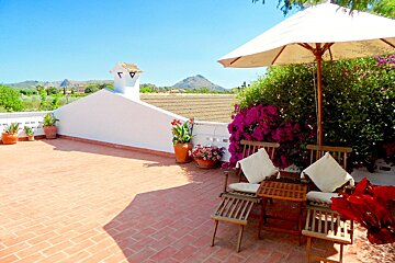A patio with a white umbrella and chairs