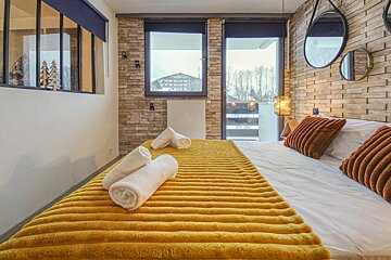 A bed with a yellow blanket and white towels on it