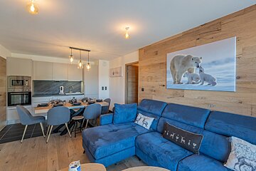 A living room with a blue couch and a picture of polar bears on the wall