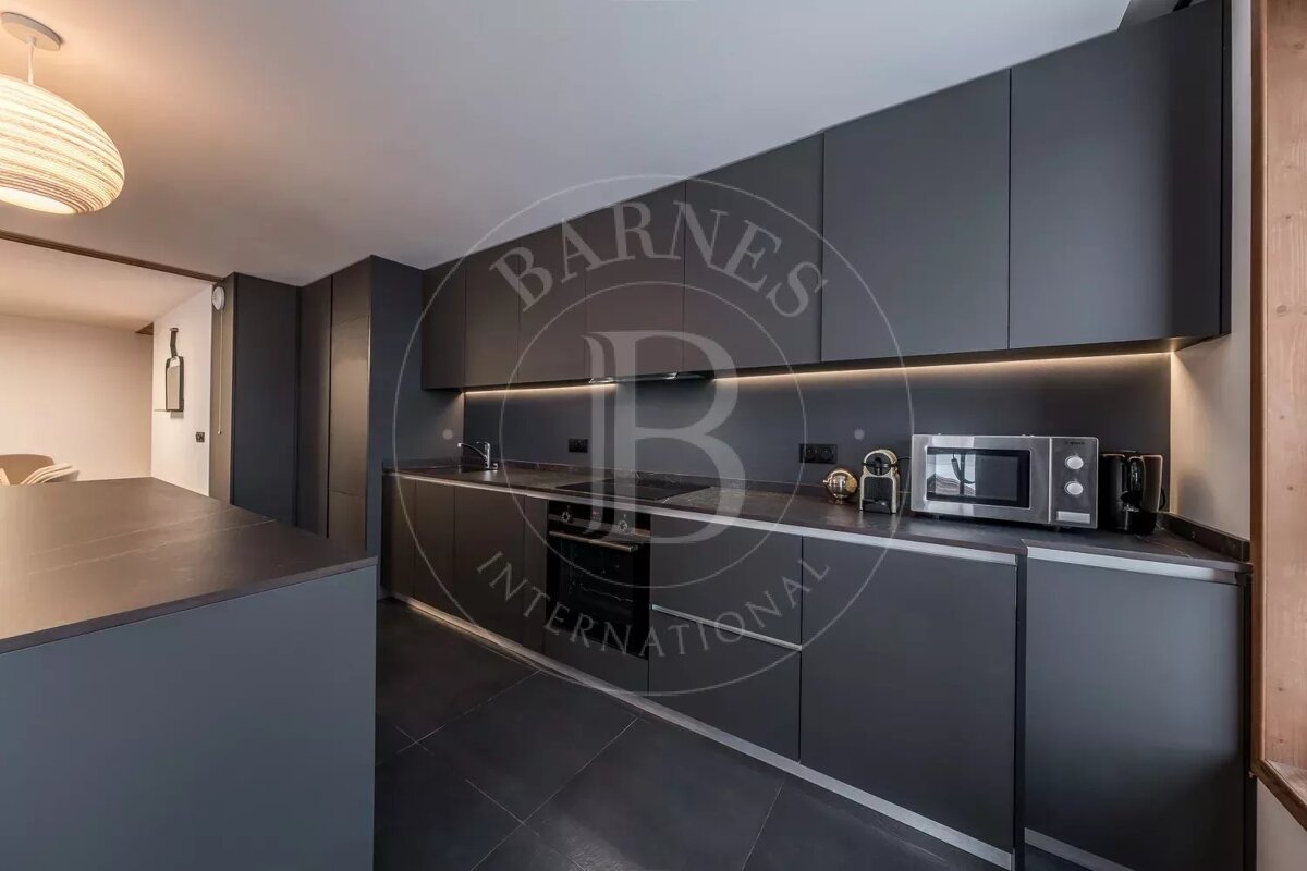 Sleek, modern dark grey kitchen with an island, integrated appliances, under-cabinet lighting, and a microwave.