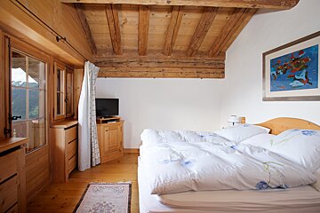 A bedroom with a painting on the wall above the bed