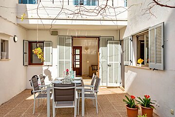 A patio with a table and chairs and potted plants