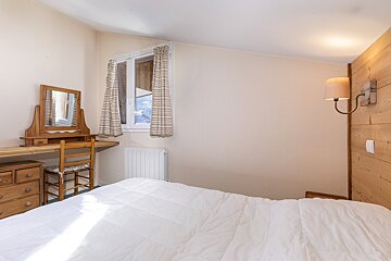 A bedroom with a bed a desk and a mirror