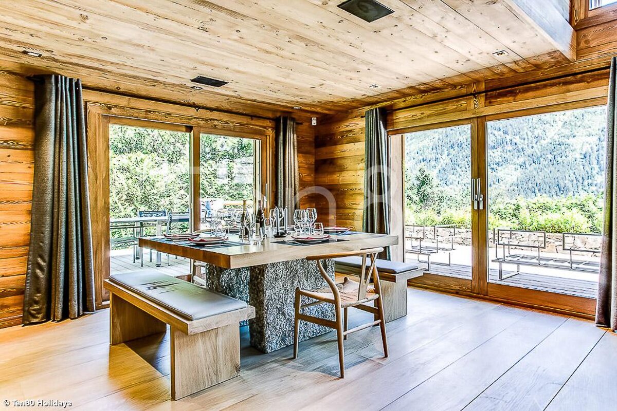A wooden dining room with a table and chairs
