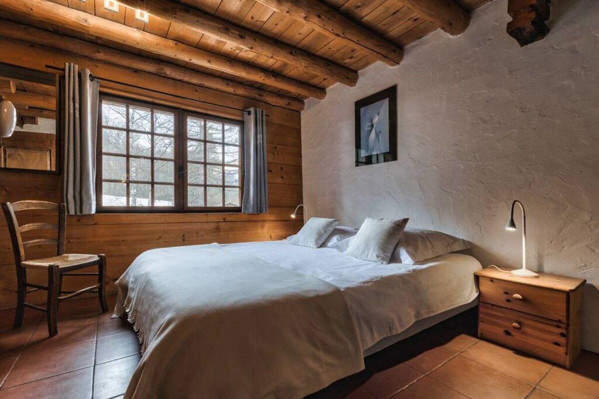 A bedroom with a large bed and a chair