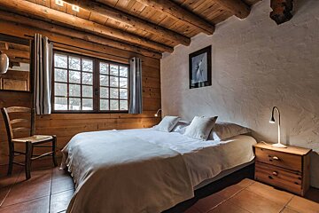 A bedroom with a large bed and a chair