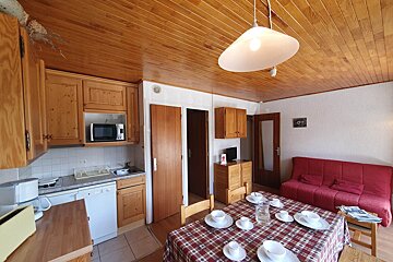 A kitchen with a dining table and a red couch