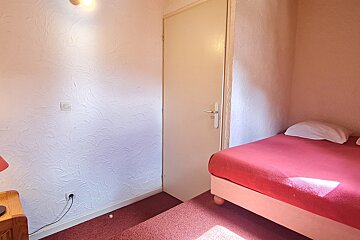 A bedroom with a red bed and a white door