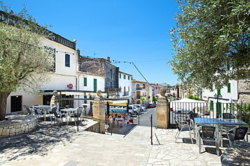 Tables and chairs in front of a building that says ' cafe ' on it