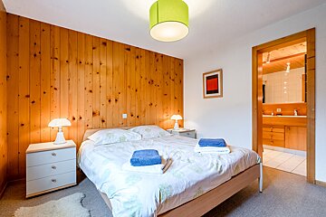A bedroom with wood paneling and a bed with blue towels on it