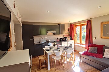 A kitchen with a table and chairs and a flat screen tv
