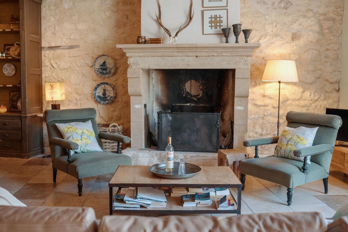 A bottle of wine sits on a table in front of a fireplace