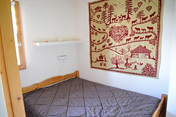 A bedroom with a bed and a tapestry on the wall