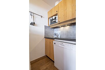 A kitchen with wooden cabinets and a white dishwasher