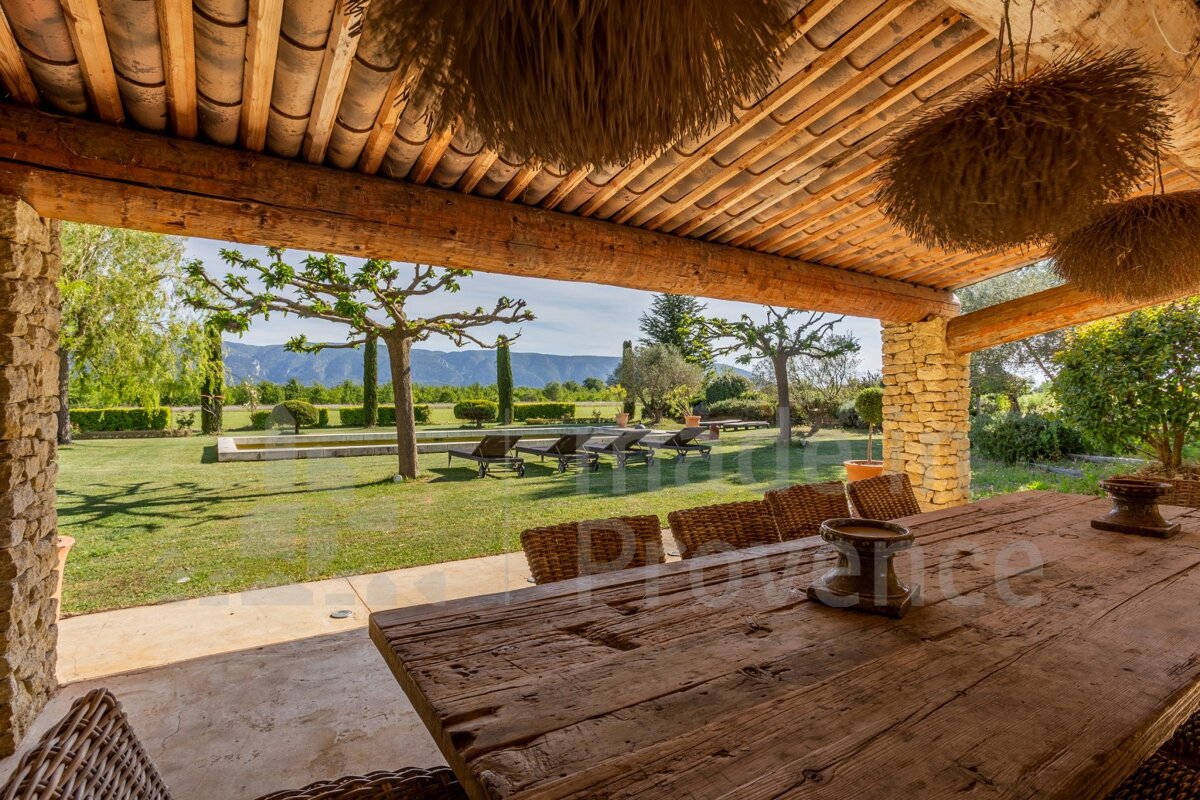 A wooden table with wicker chairs under a wooden roof with the word provence in the corner