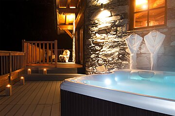 A hot tub is lit up in front of a stone wall