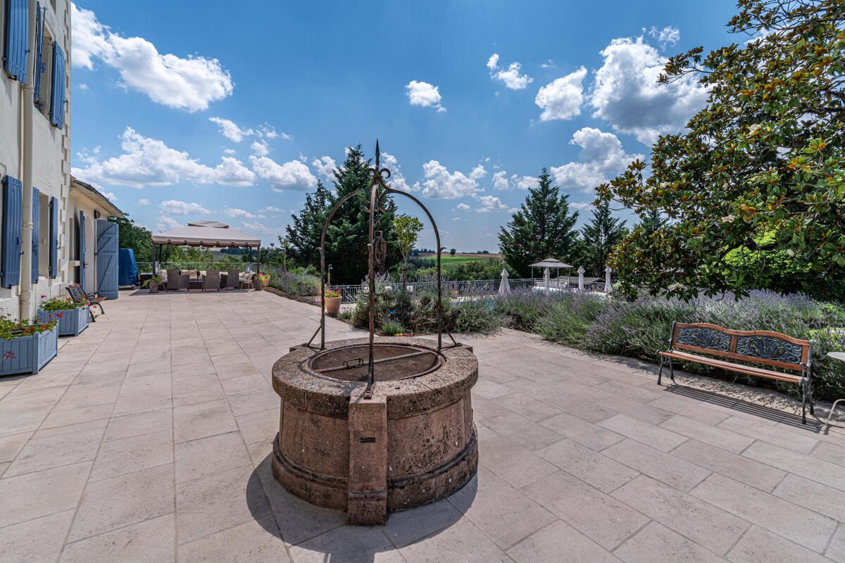 A stone well sits on a patio next to a bench