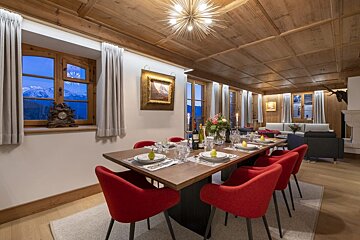 A dining room with red chairs and a wooden table