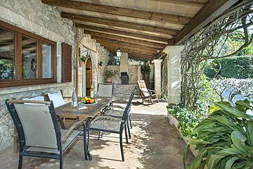 A table with a plate of fruit on it sits on a porch