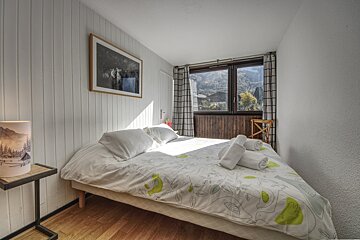 A bedroom with a bed a lamp and a picture on the wall