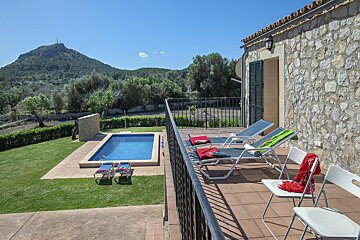 A balcony overlooking a swimming pool with a mountain in the background