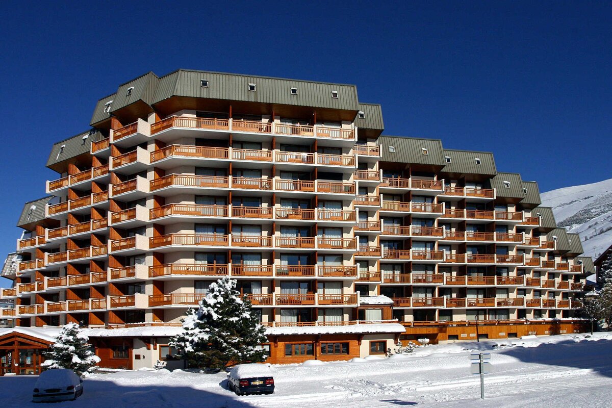 A large building with a lot of balconies is covered in snow