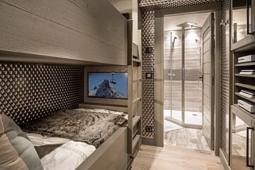 A bedroom with a bunk bed and a television on the wall