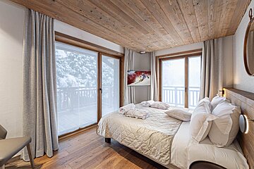 A bedroom with a large bed and a painting on the wall