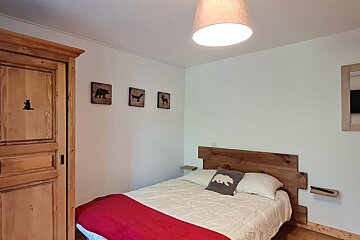 A bedroom with a bed with a bear pillow on it