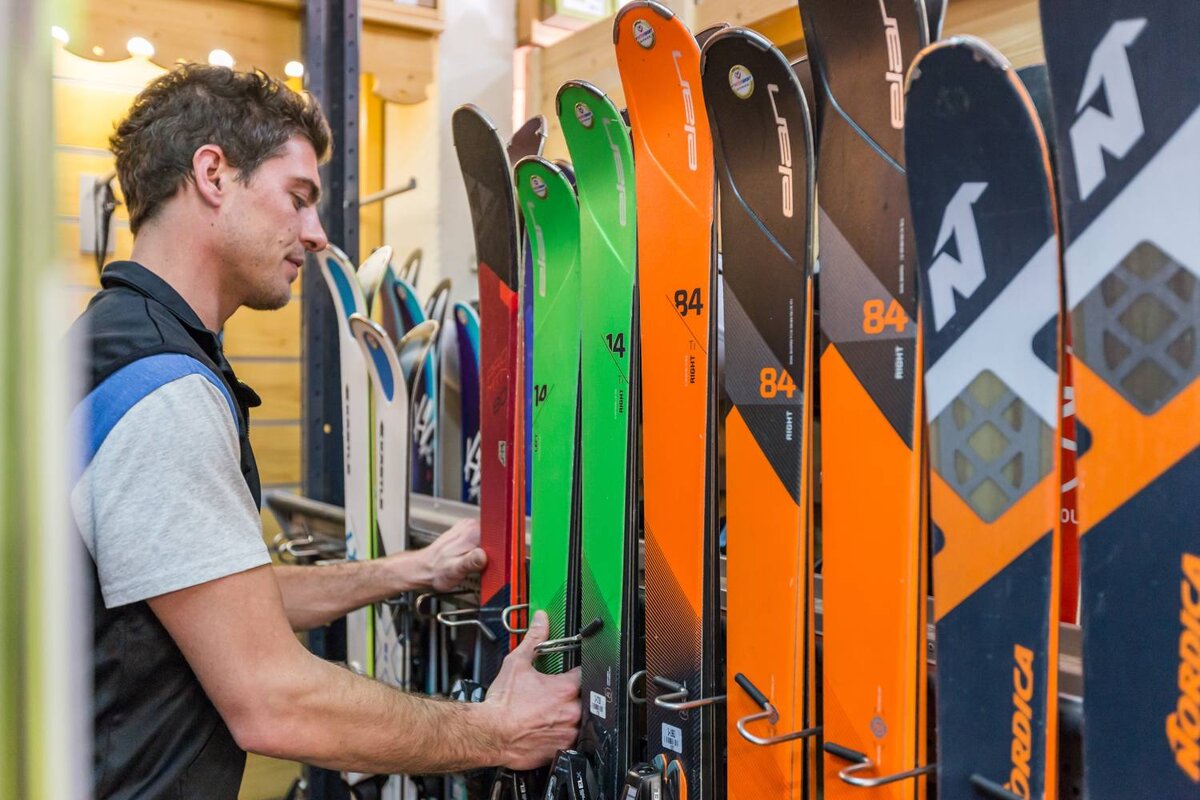 A man is looking at skis with the number 84 on them