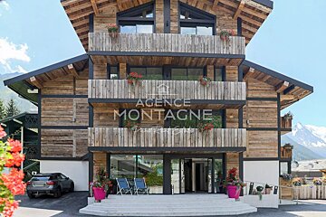A modern multi-story wooden chalet with balconies and flower boxes.