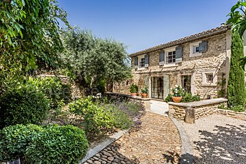 A stone house with a cobblestone driveway leading to it