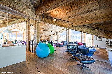 A living room with wooden ceilings and a black chair