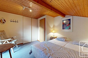 A bedroom with a bed a chair and a painting on the wall