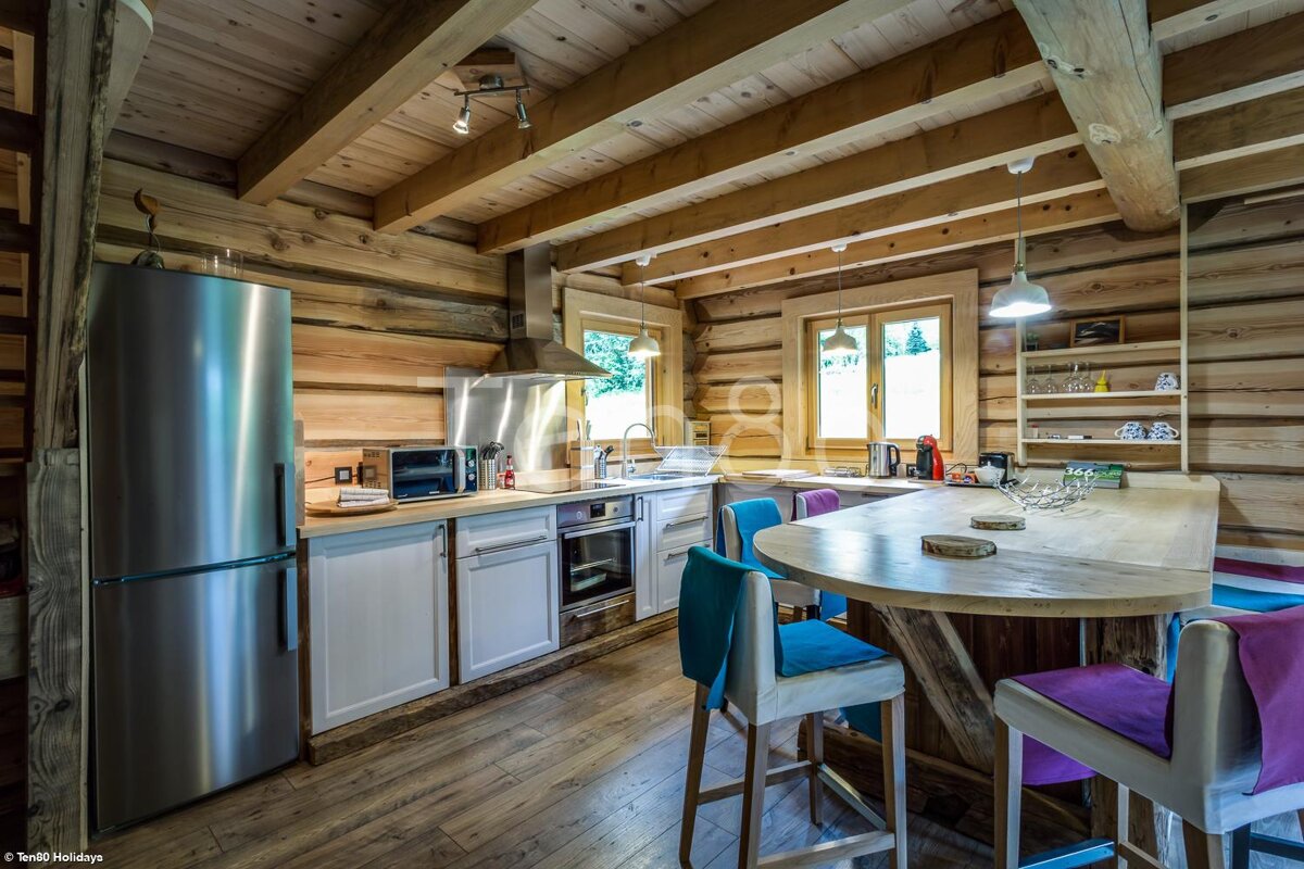 A kitchen in a log cabin with a stainless steel refrigerator